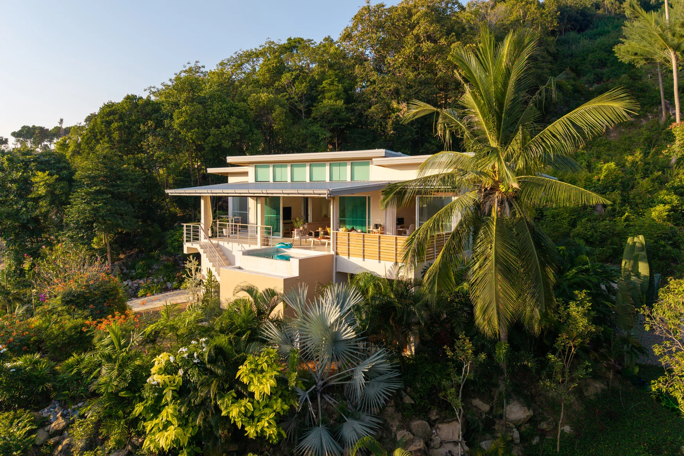 Villa Stella Marina exterior framed by coconut palms and lush hillside in Koh Phangan